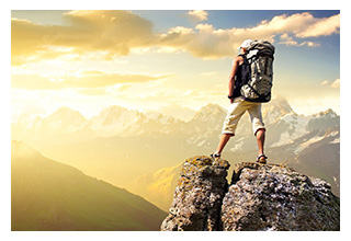 Backbacker watching the sunset from a high rock